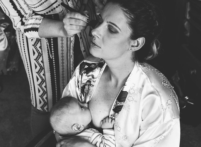 Mother breastfeeding her baby while getting her makeup done