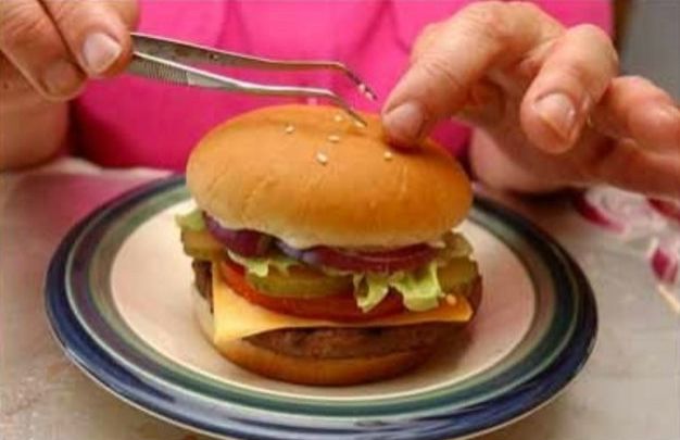 A person putting sesame seeds on a burger bun
