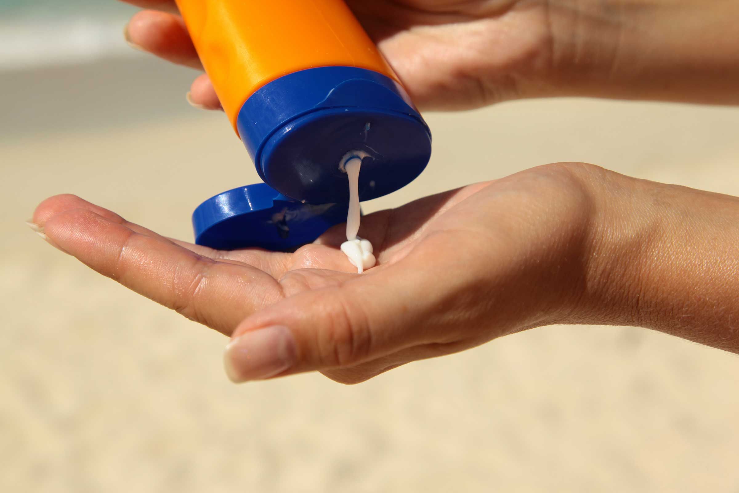 A hand squeezing out suntan lotion