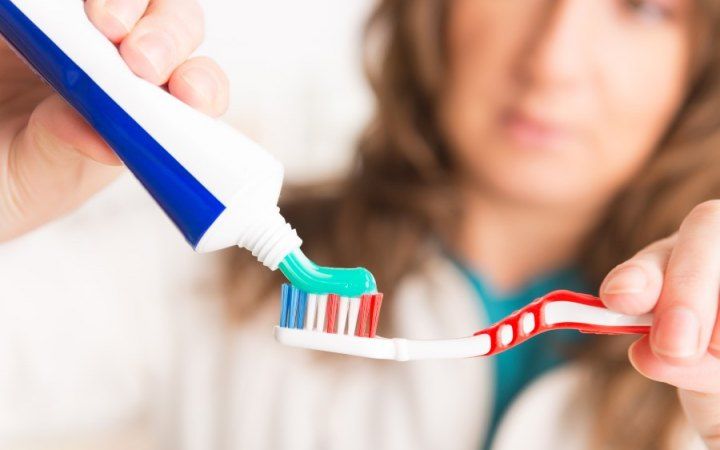 A woman putting toothpaste on a toothbrush