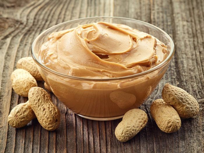 A bowl of peanut butter surrounded by peanuts