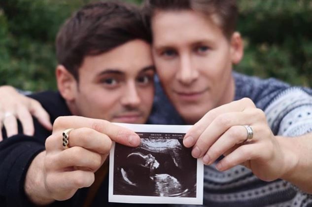 Tom Daley and Dustin Lance Black holding the sonogram of their son