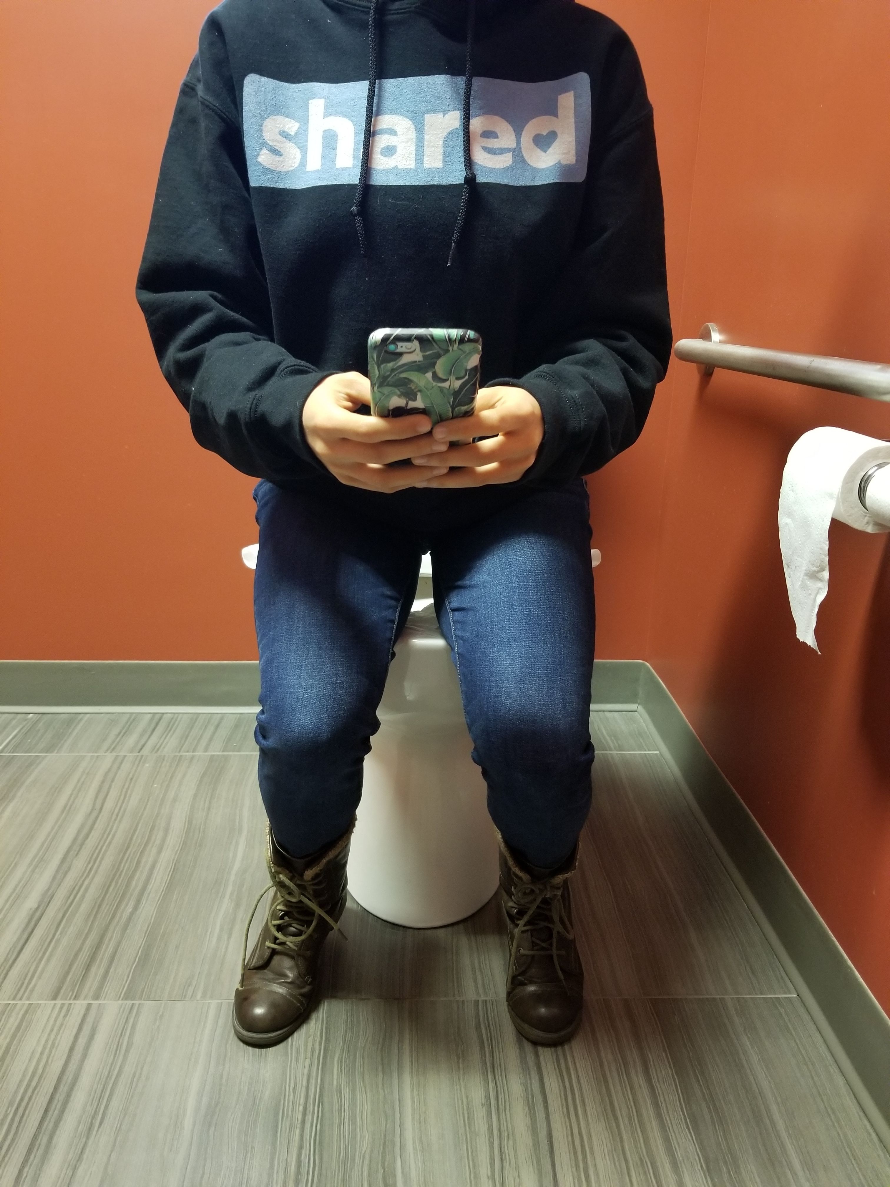 sitting on toilet seat with phone 