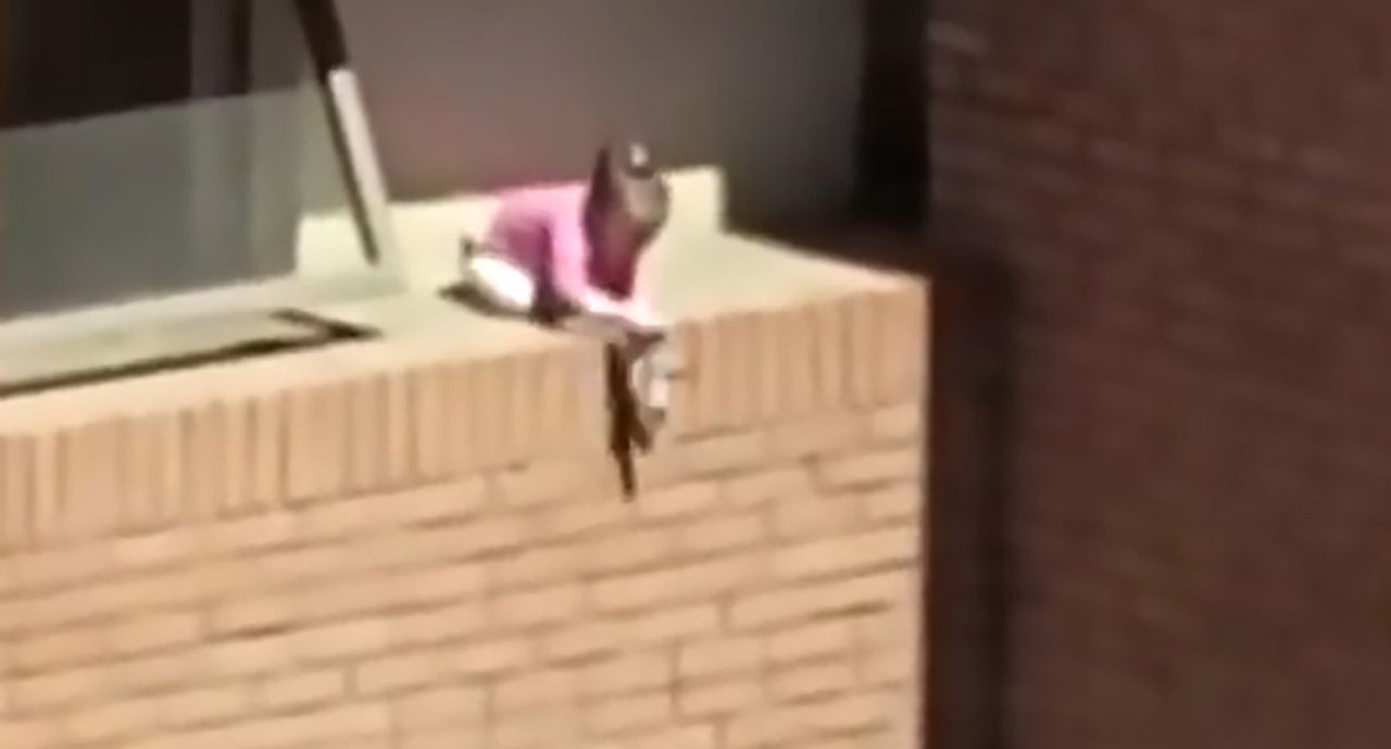 Girl plays with a doll on a ledge