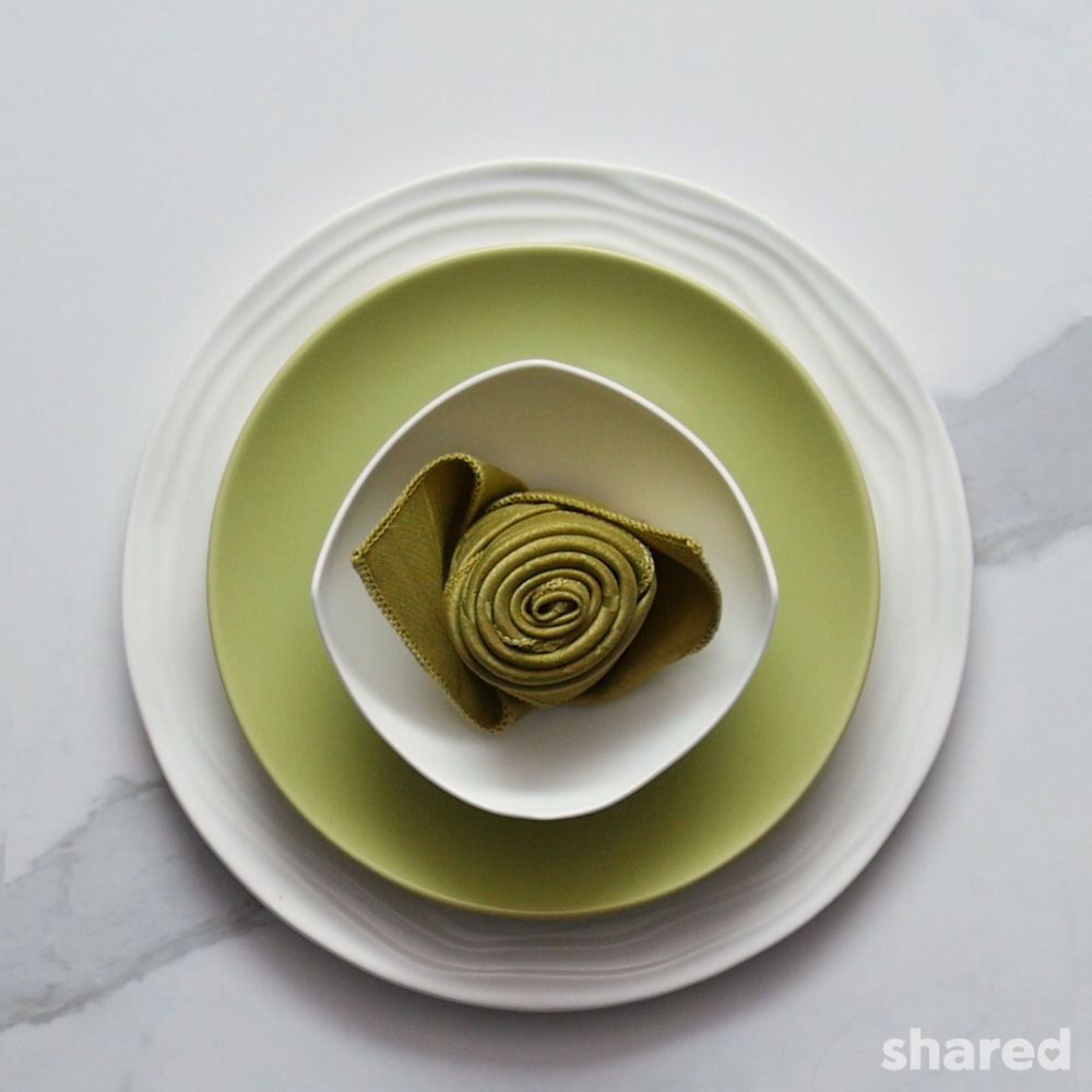 green and white place setting featuring green rosebud napkin fold