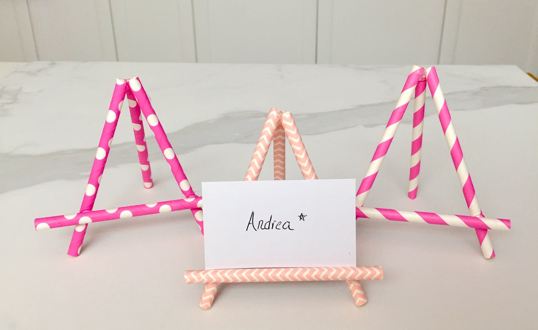 Three pink place card holders made out of paper straws