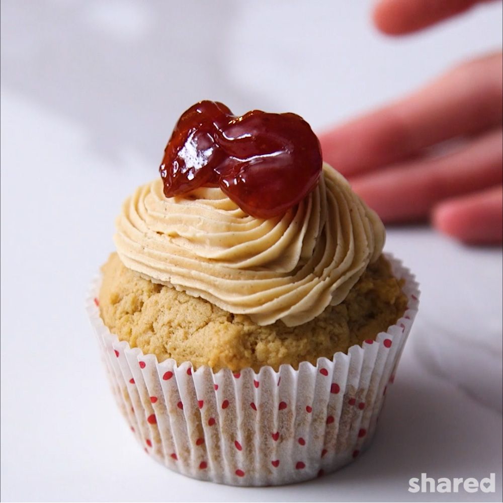Peanut Butter cupcake in red and white polkadot liner with swirled peanut butter icing and strawberry jam topping