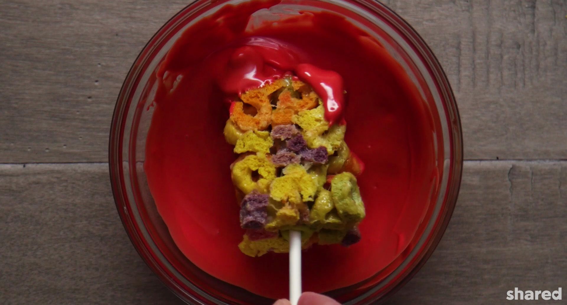 Fruit Loop Snack being dipped into a melted red candy melts