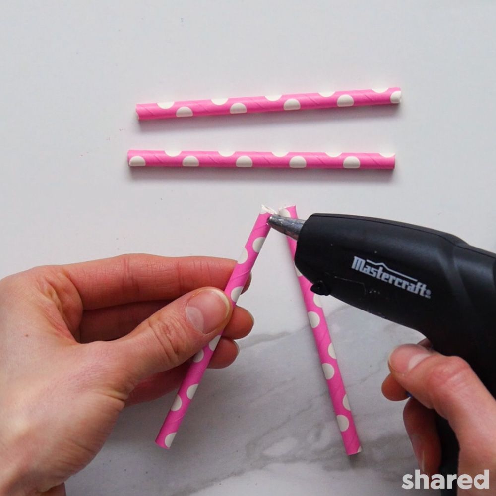 Pink paper straws cut in half being glued together