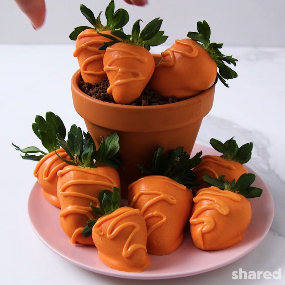 Strawberries on a pink plate dipped in orange chocolate to look like carrots