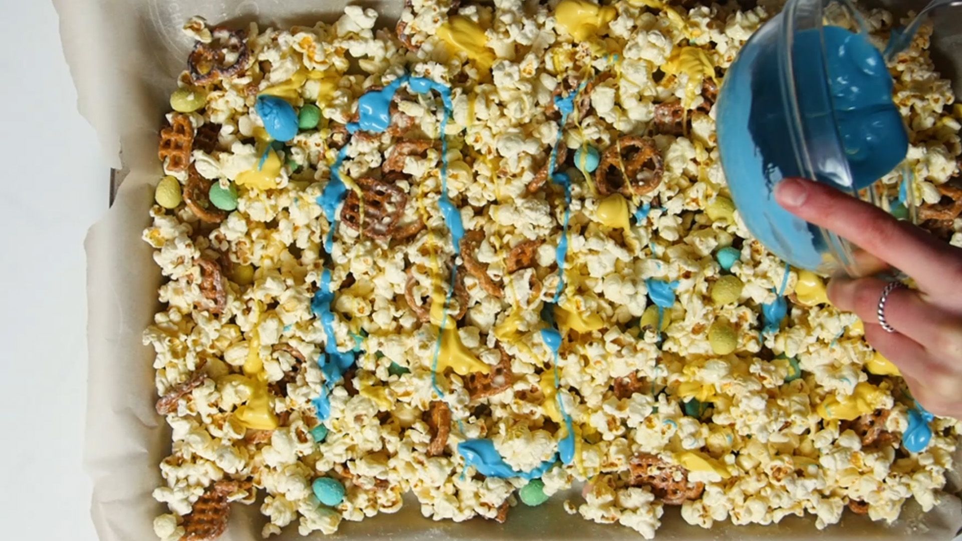 candy melts being poured onto popcorn