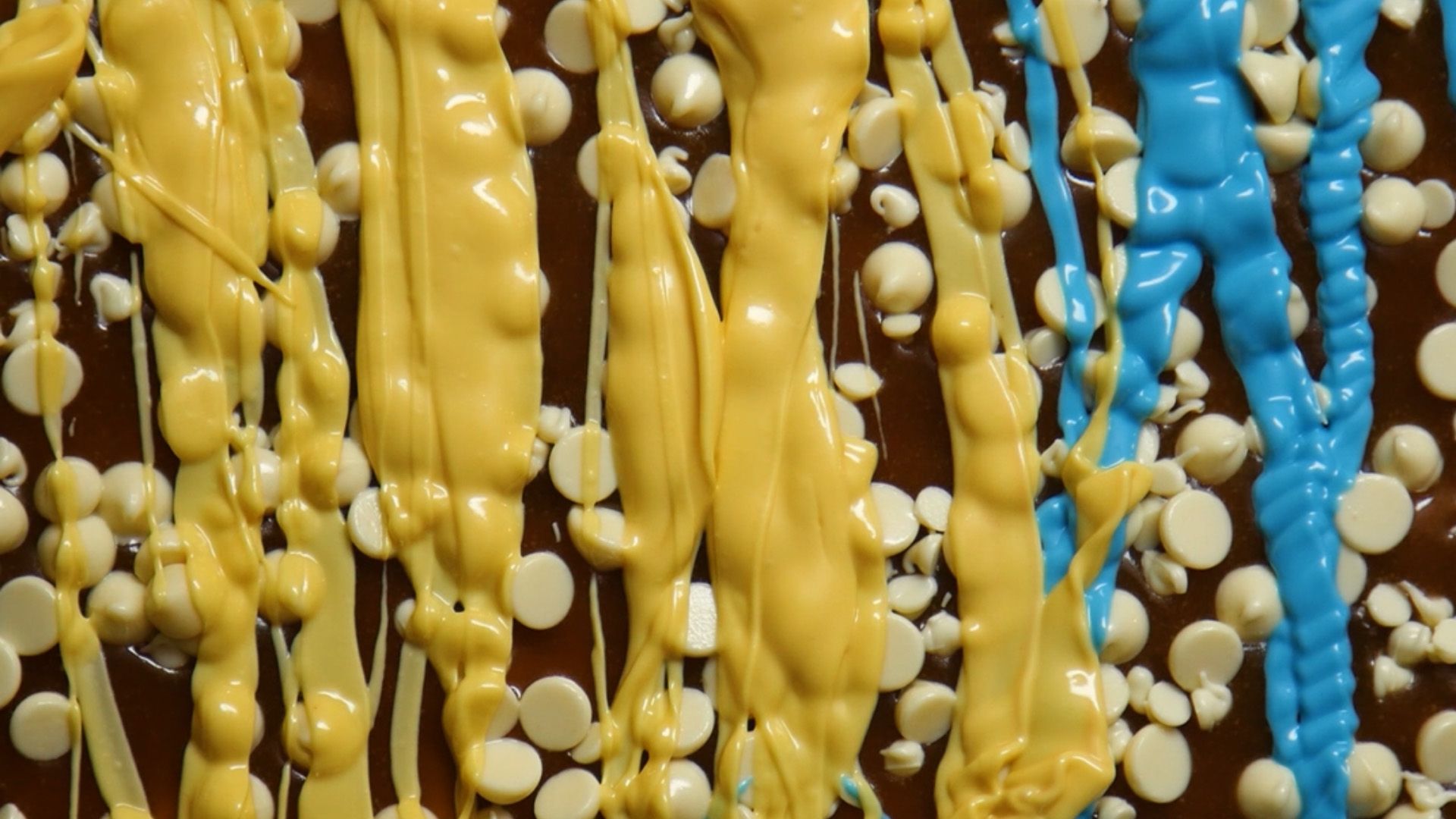 close up of white chocolate chips and candy melts melting on top of toffee