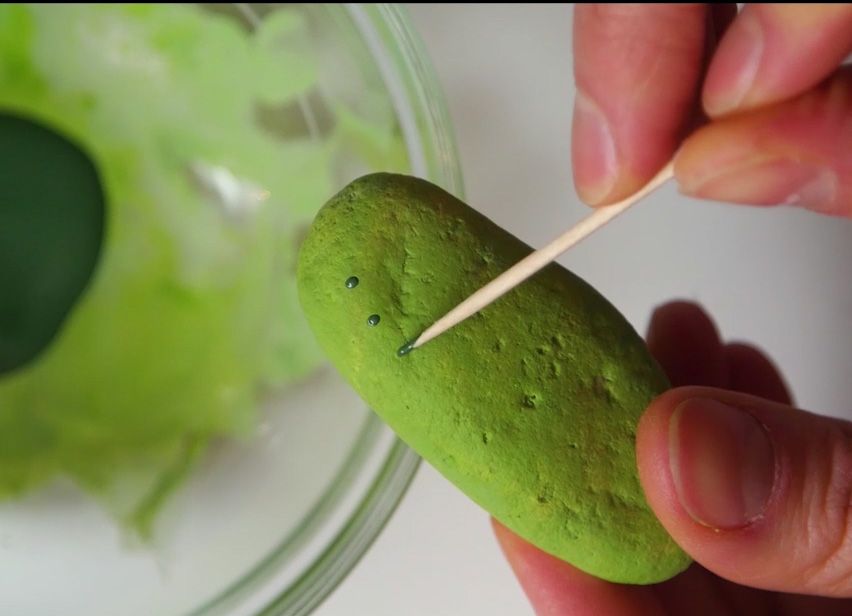 fake spikes being painted onto a smooth green rock