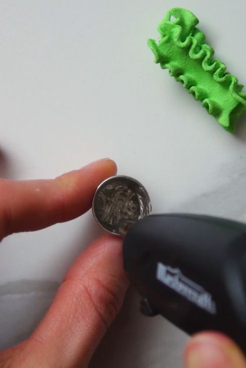 hot glue being squeezed into a silver thimble