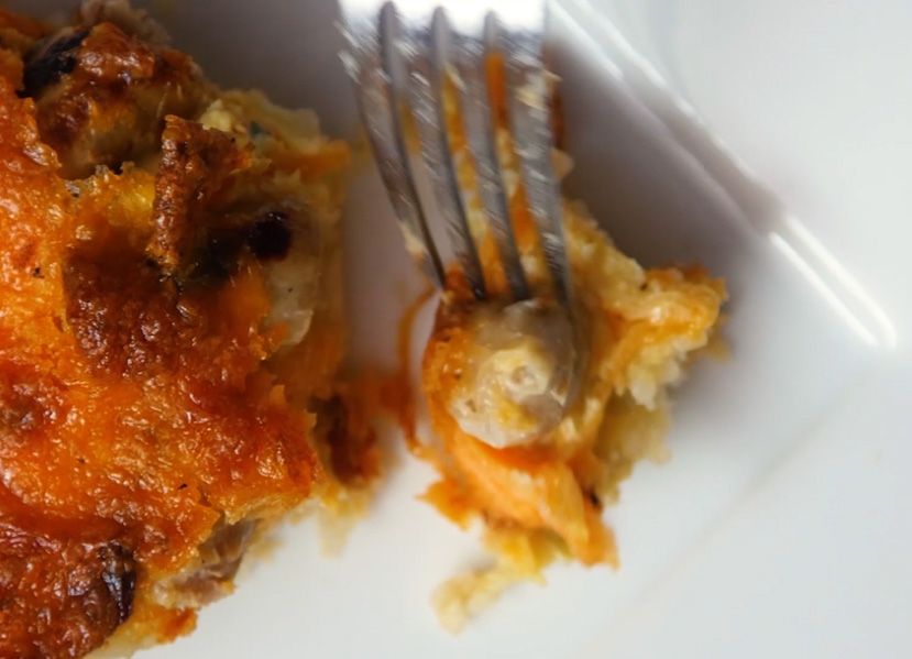 a cooked slice of meat lovers quiche being scooped up on a sliver fork