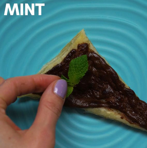 mint being placed on a cooked nutella puff pastry