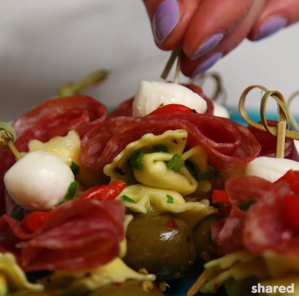 close up of an antipasto skewer being picked up off of a tray