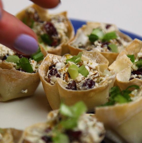 fingers grabbing for a pistachio goat cheese phyllo cup on a serving tray 