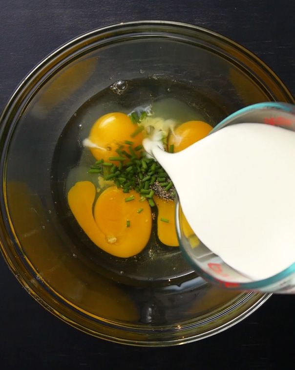 milk being poured into glass bowl full of eggs and spices
