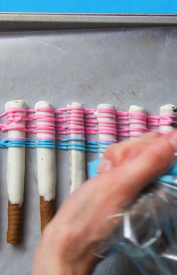 white chocolate wafer sticks being drizzled with colored candy melts 