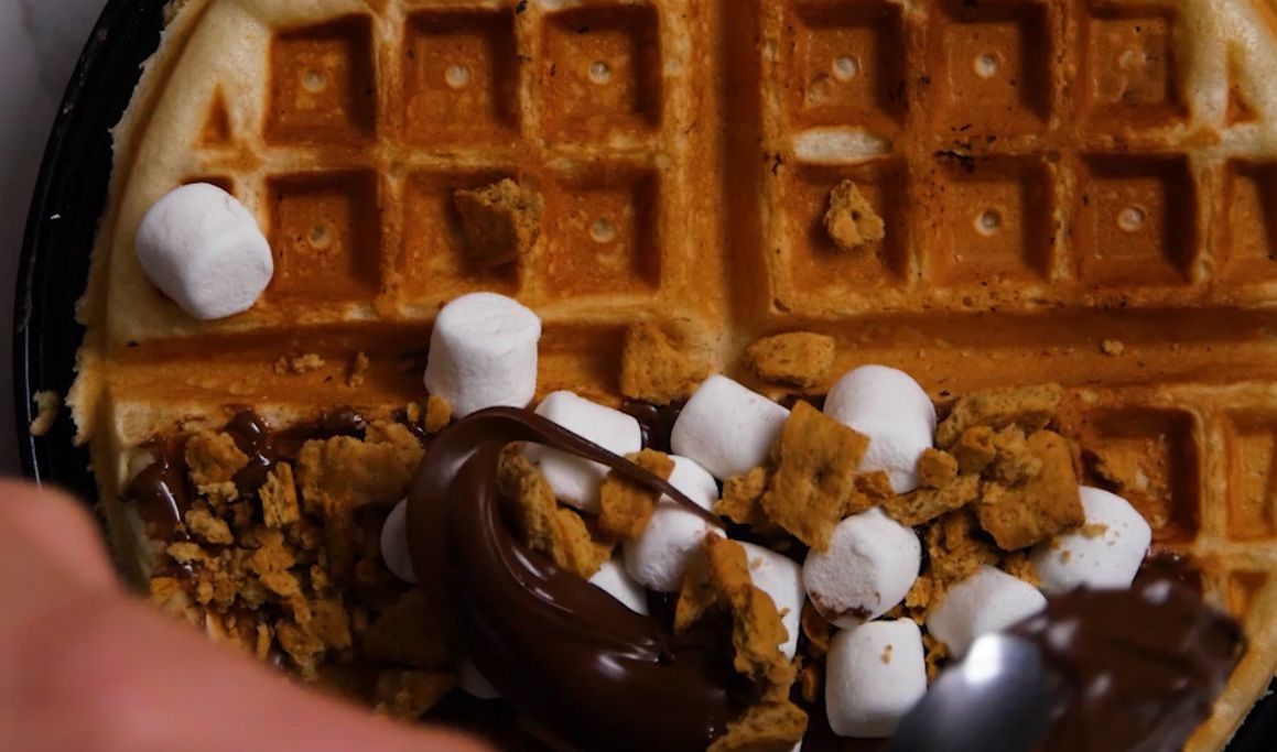 smore waffle being topped with chocolate and marshmallows